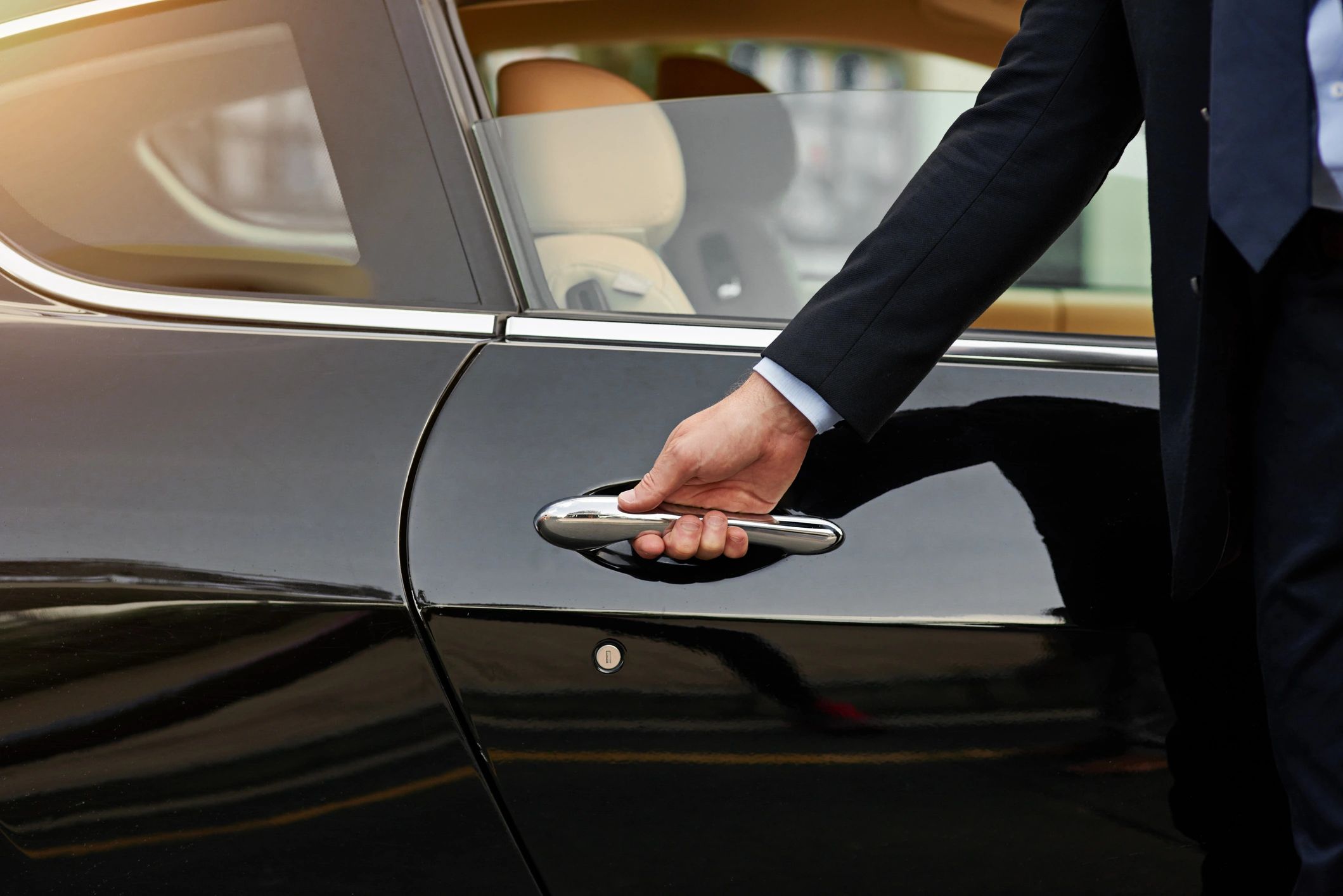 Chauffeur opening a luxury car door for a passenger