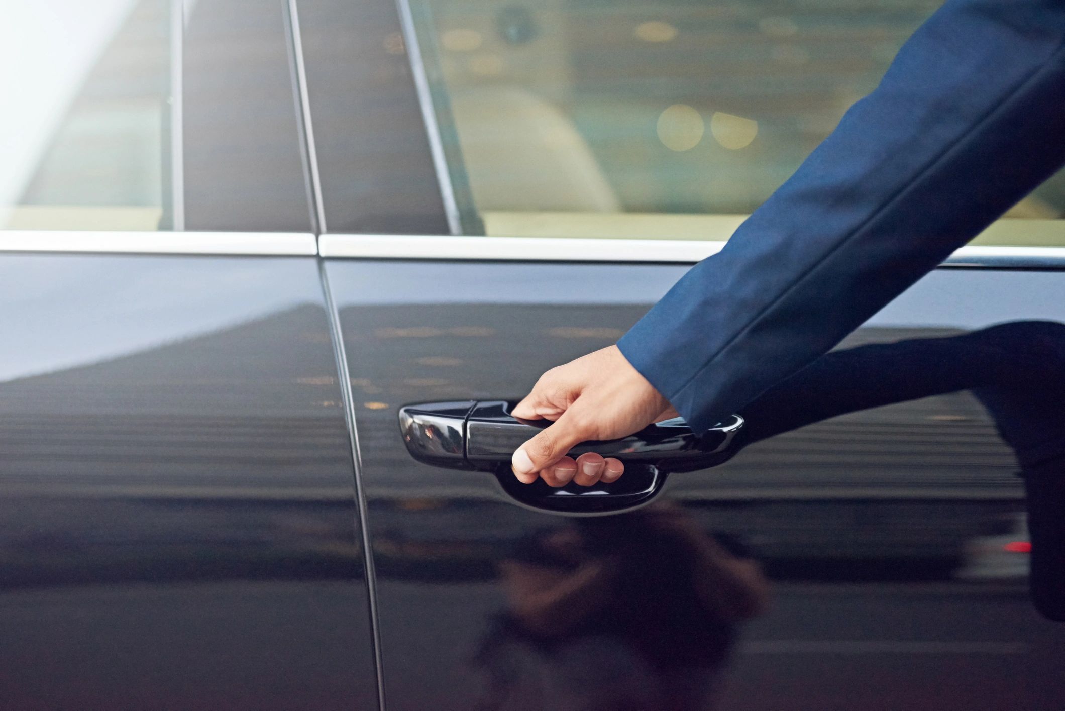 Professional chauffeur opening a luxury car door